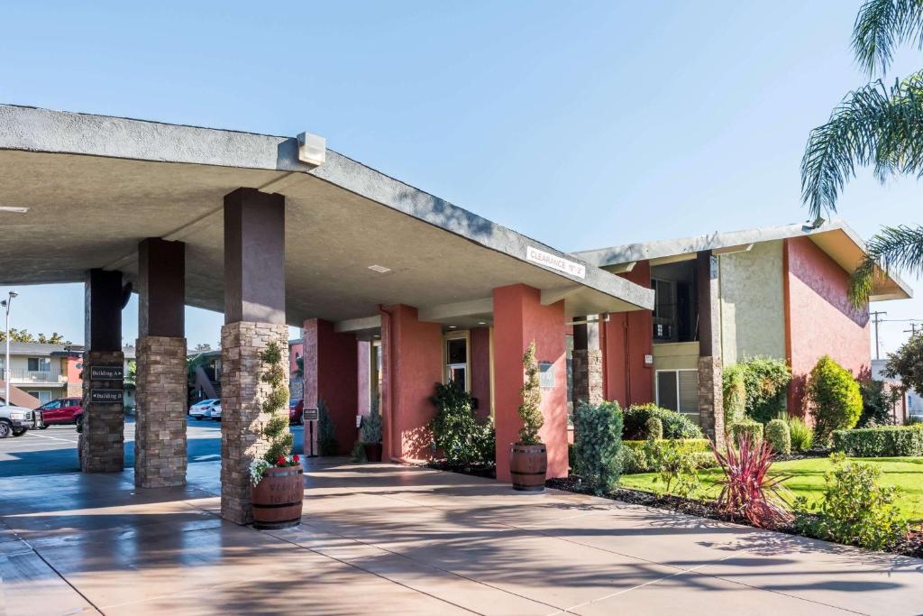 un grand bâtiment avec des palmiers et un trottoir dans l'établissement Days Inn & Suites by Wyndham Lodi, à Lodi