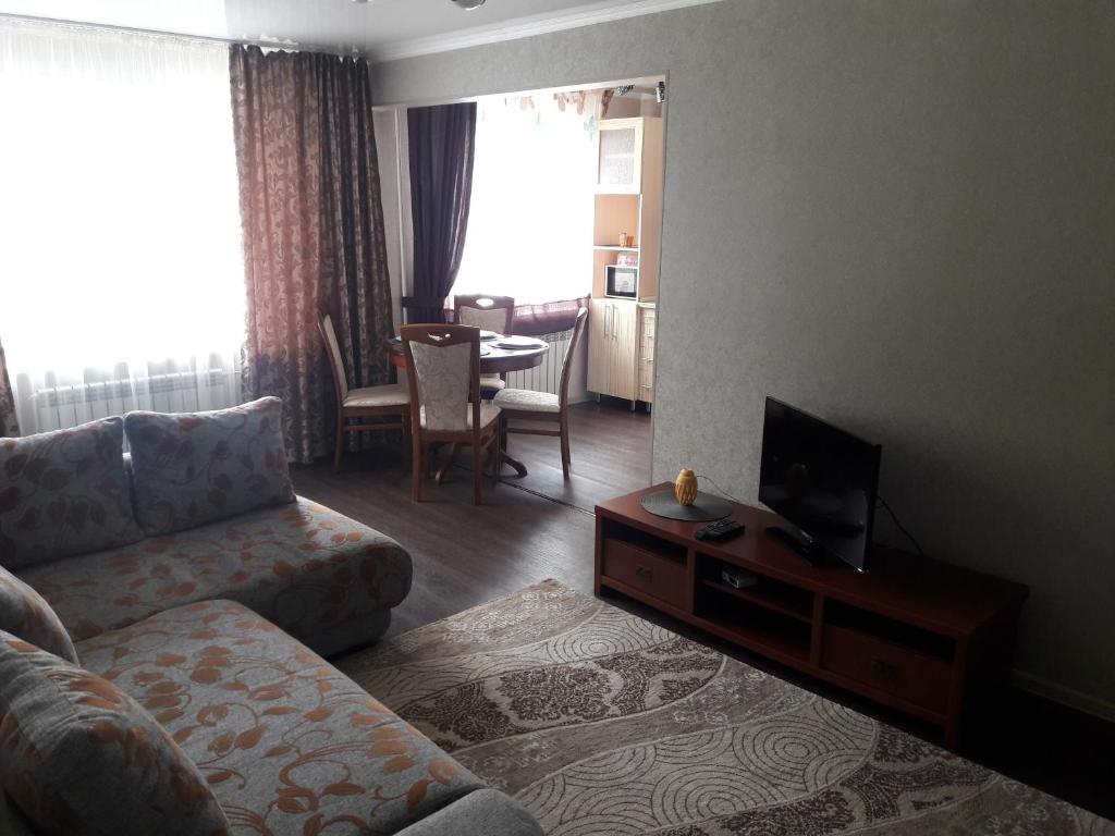 a living room with a couch and a tv at Apartments on 23,1 Nаzarbaeva Ave in Ustʼ-Kamenogorsk