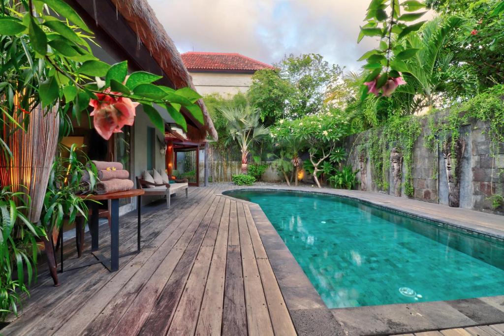 una piscina con terraza de madera junto a una casa en Villa Sham, en Seminyak
