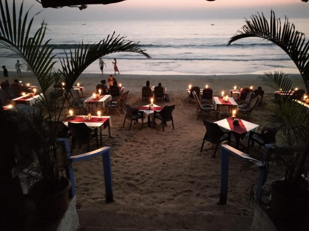 gente sentada en las mesas de la playa por la noche en Royal Touch Beach Huts, en Palolem