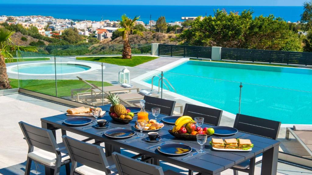 a table with food on it next to a swimming pool at Orama 4 bedroom Villa with private pool in Hersonissos