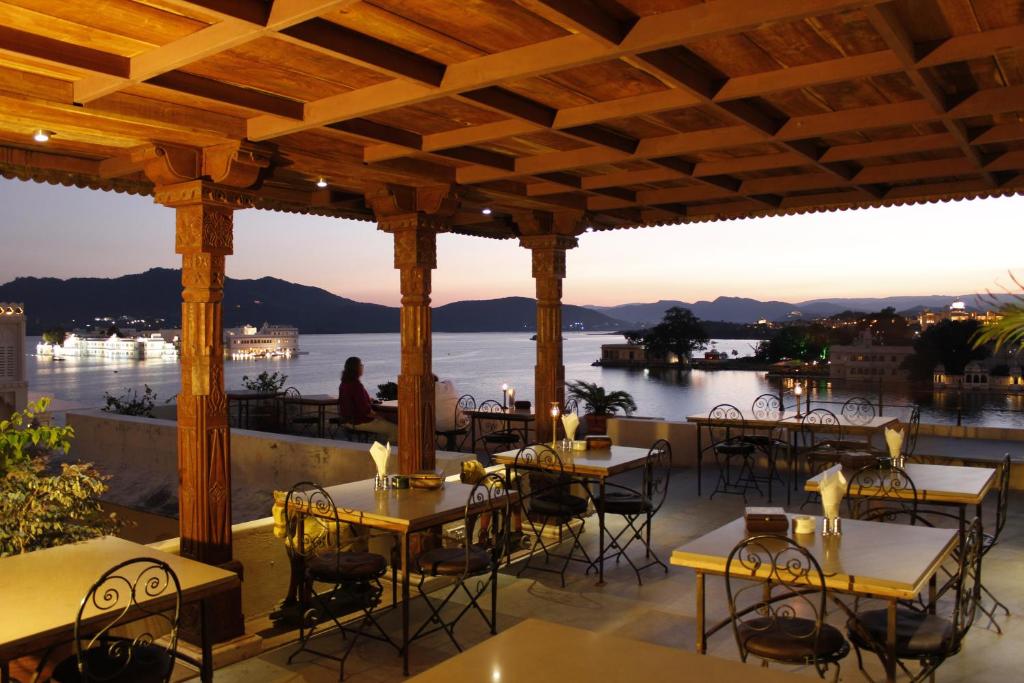 a restaurant with tables and chairs and a view of the water at Kankarwa Haveli in Udaipur