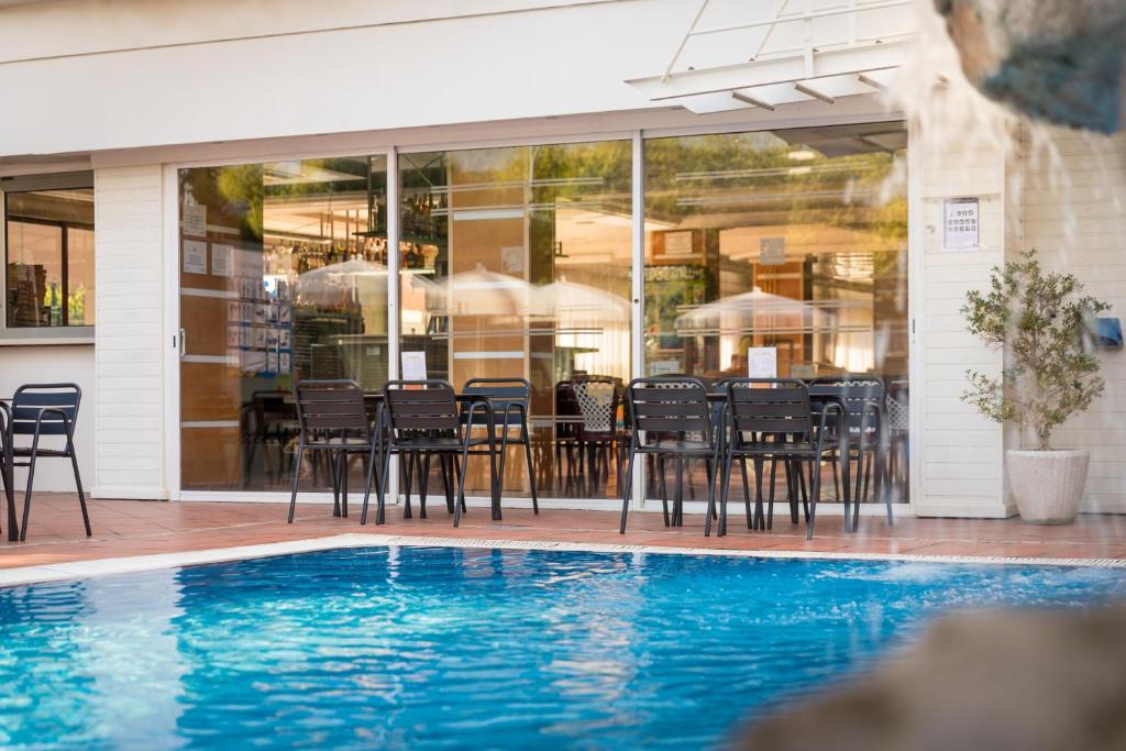 una piscina con sillas y una mesa frente a un edificio en htop Summer Sun #htopEnjoy, en Santa Susanna