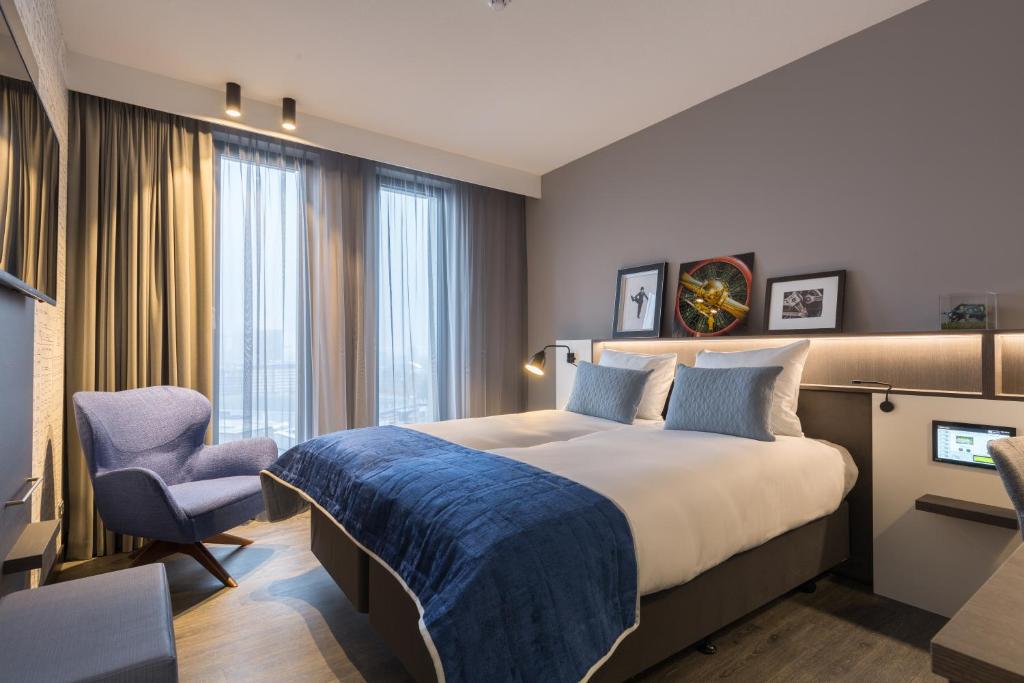 um quarto de hotel com uma cama grande e uma cadeira em Postillion Hotel Amsterdam em Amsterdã