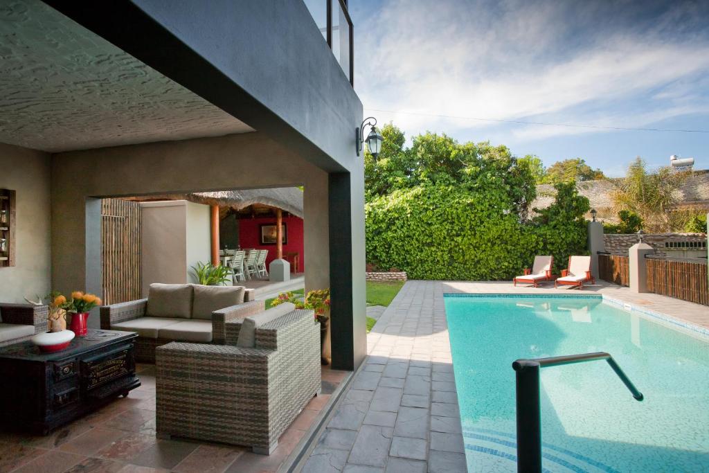a swimming pool with a patio furniture and a house at Miles B&B Guest House in Oudtshoorn