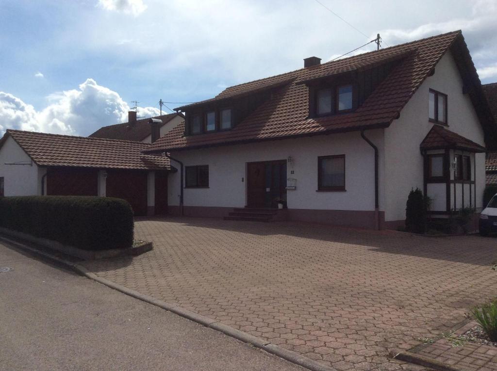 a white house with a tiled roof and a driveway at Ferienwohnung-Loesch in Neuenburg am Rhein