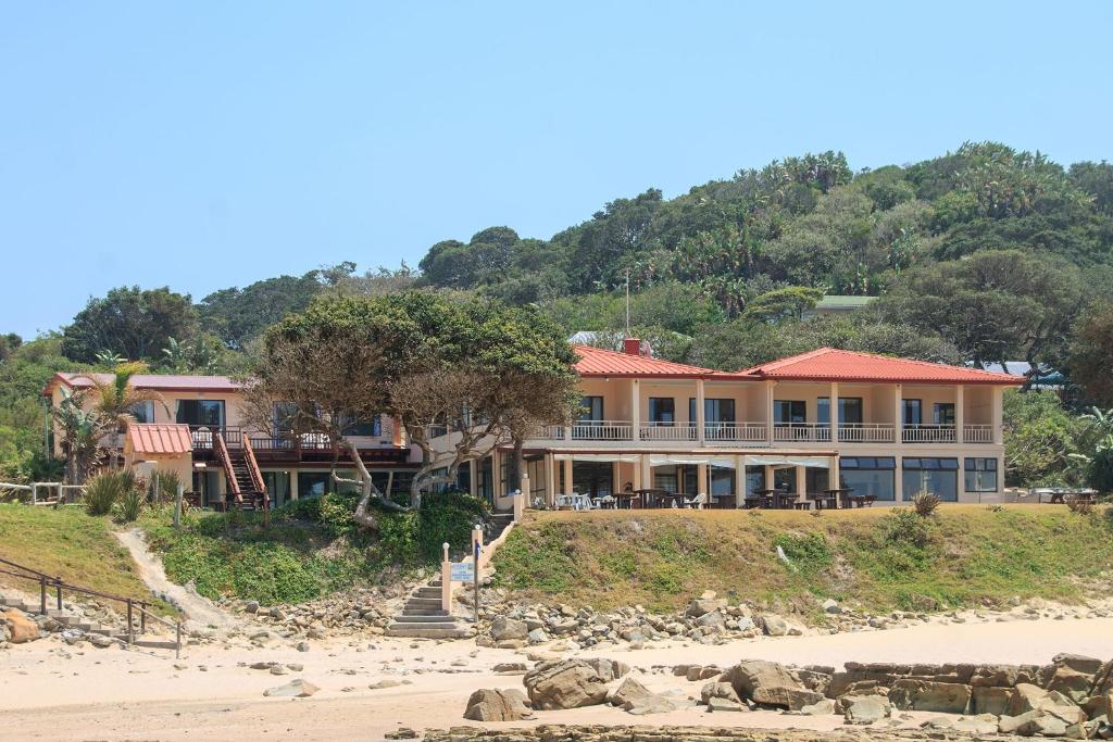 a large house on the beach next to the ocean at Neptunes Cove in Kei-mouth Village