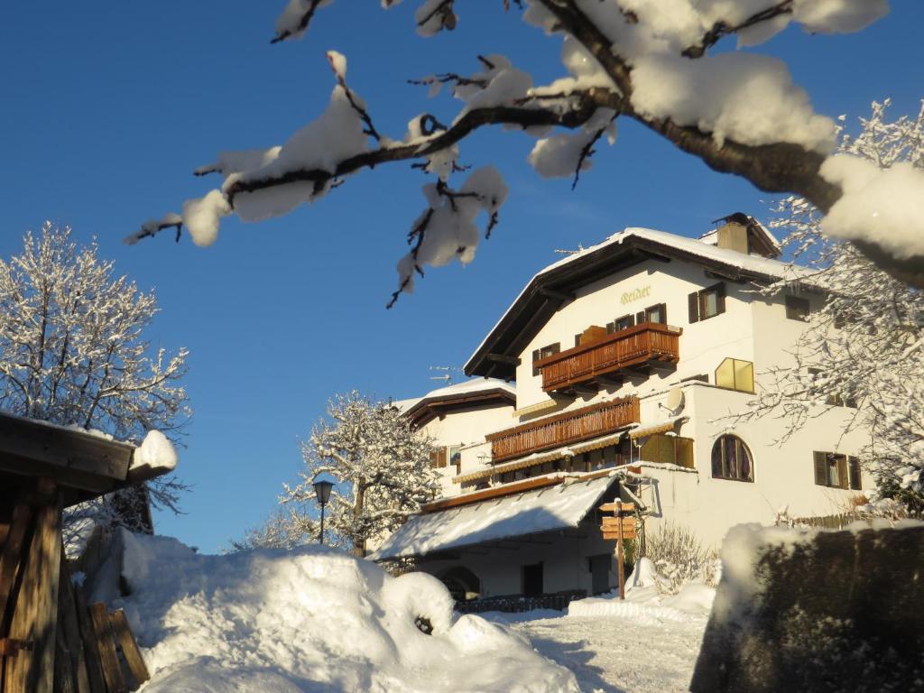 a building in the snow with snow covered trees at Garni Reider in Meltina