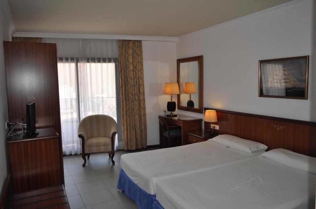 a bedroom with a bed and a desk and a television at Hostal Vila del Mar in Lloret de Mar