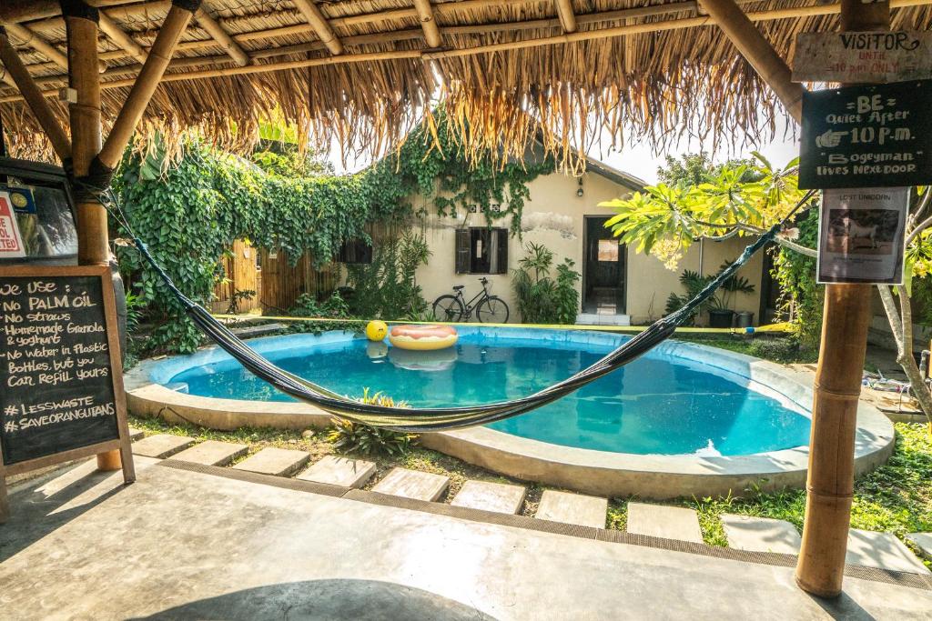 a hammock in front of a house with a swimming pool at Losmanos Hostel in Yogyakarta