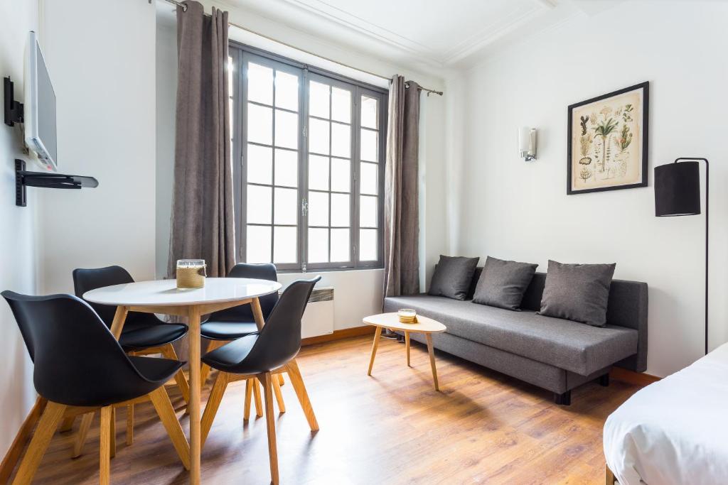 ein Wohnzimmer mit einem Sofa, einem Tisch und Stühlen in der Unterkunft CMG Palais des Congrès/ Ternes in Paris