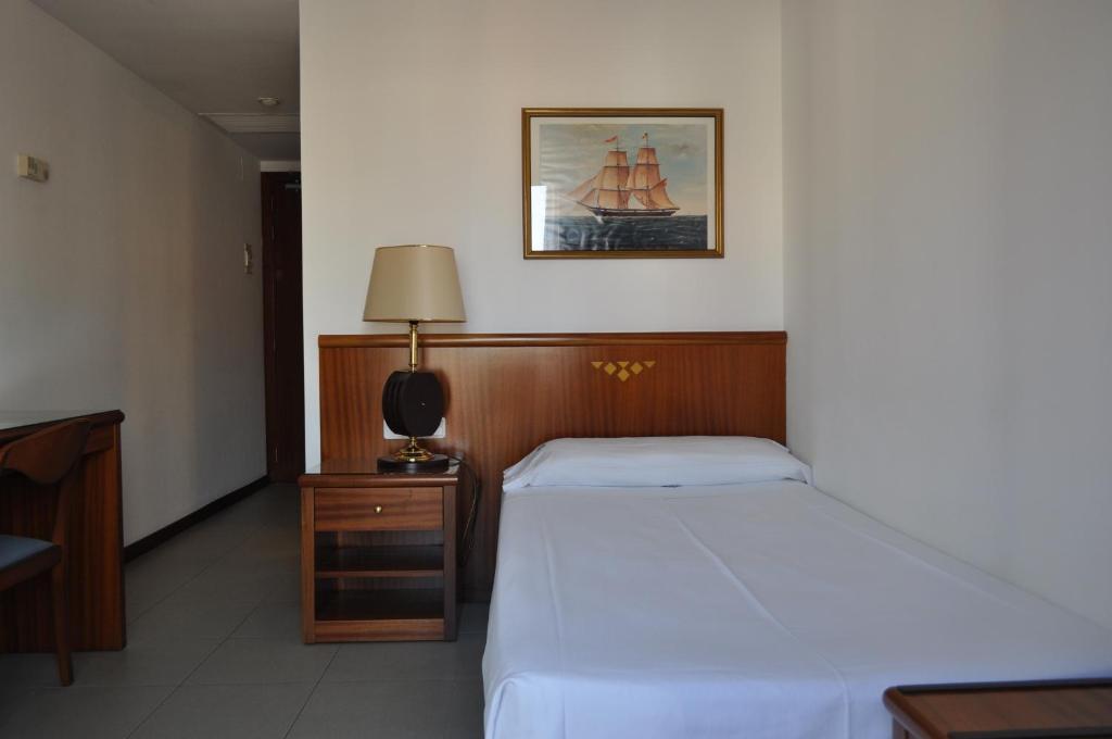 a bedroom with a bed and a desk with a lamp at Hostal Vila del Mar in Lloret de Mar