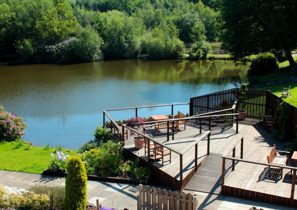 une terrasse en bois avec des tables et des chaises à côté d'un lac dans l'établissement Inn On The Lake, à Gravesend