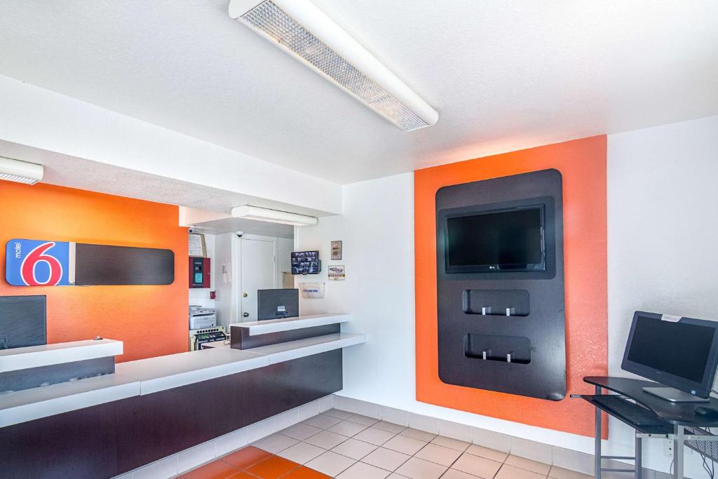 a waiting room with orange walls and a tv at Motel 6-Ardmore, OK in Ardmore