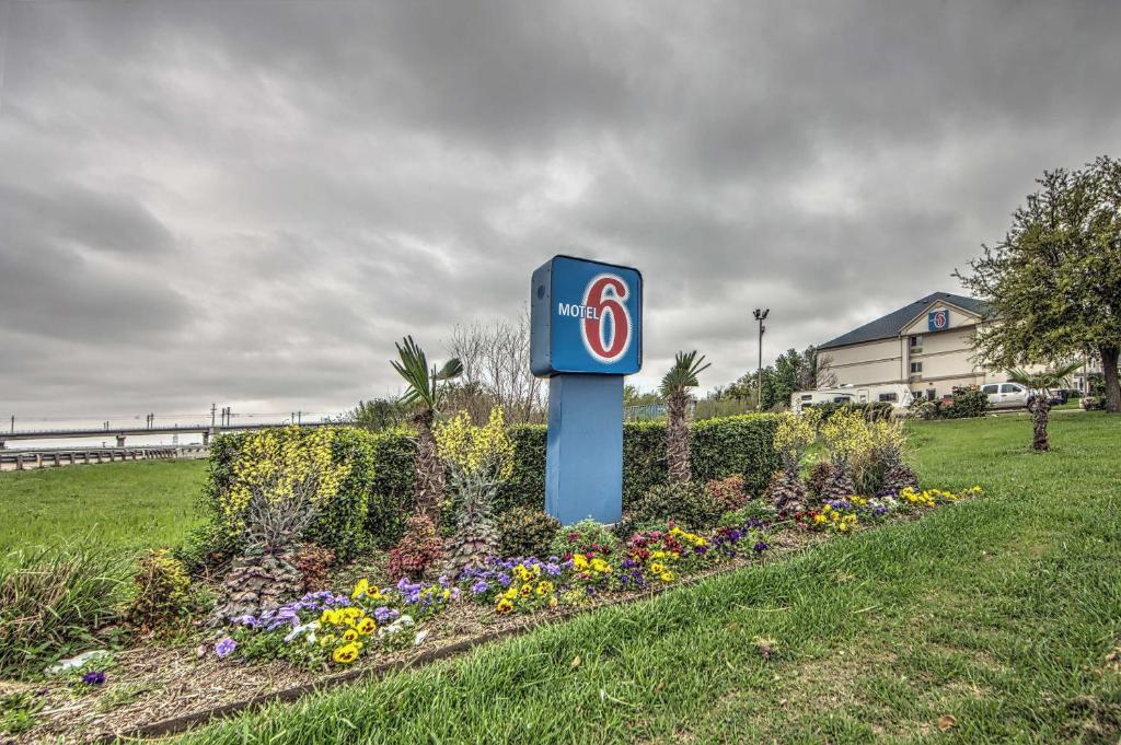 a blue gas station sign in a field with flowers at Motel 6-Dallas, TX - Northwest in Dallas