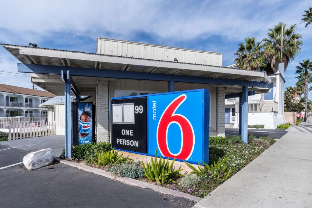 una gasolinera con un cartel de una persona delante de ella en Motel 6-Oceanside, CA, Marina, en Oceanside