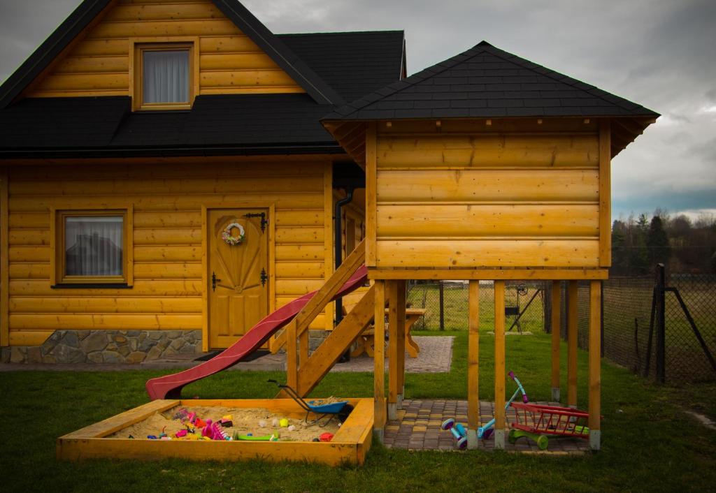 a play house with a slide in front of a house at Domek w Ogrodzie in Szaflary