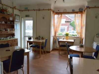 a dining room with tables and chairs and a window at White Heather Guest House in Mablethorpe