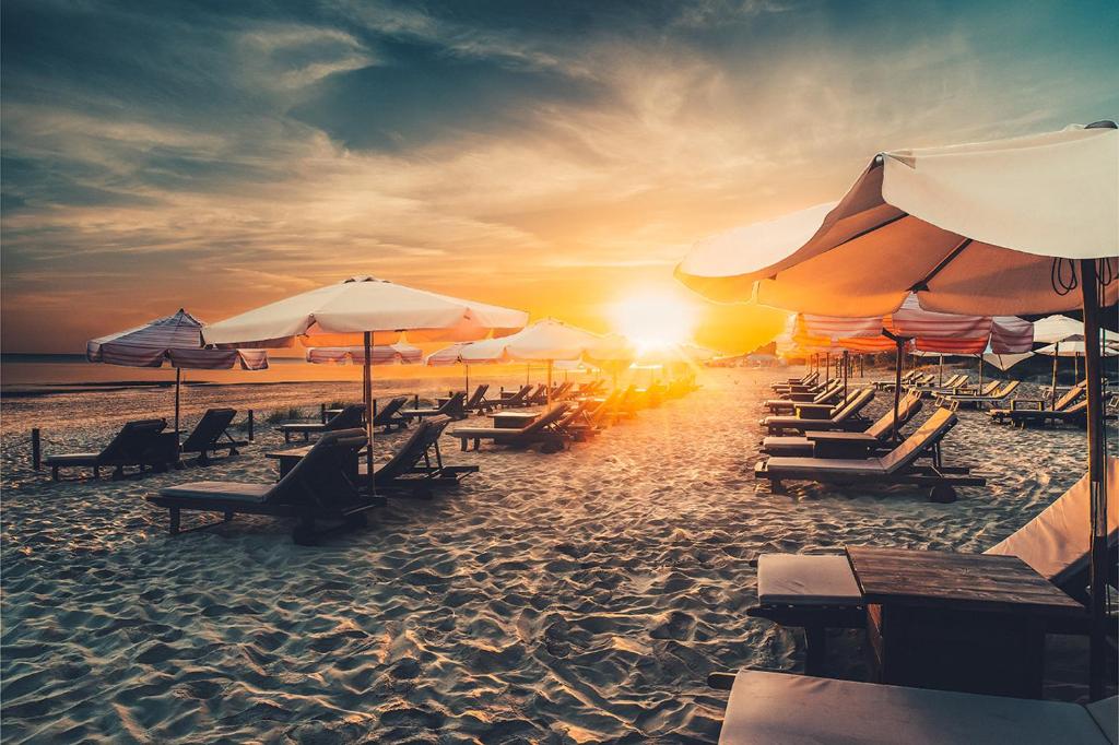 een groep strandstoelen en parasols op een strand bij Boutique Hotel Light House Jurmala in Jūrmala