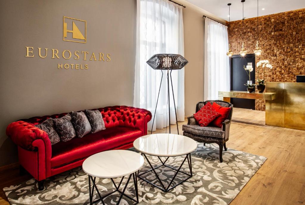 a living room with a red couch and two chairs at Eurostars Azahar in Córdoba