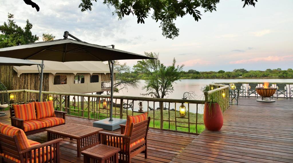 a wooden deck with chairs and an umbrella at Jackalberry Chobe in Kasane