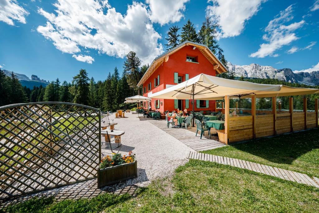 a red house with a fence and a patio at La Locanda del Cantoniere - Ciasa Vervei in Cortina dʼAmpezzo
