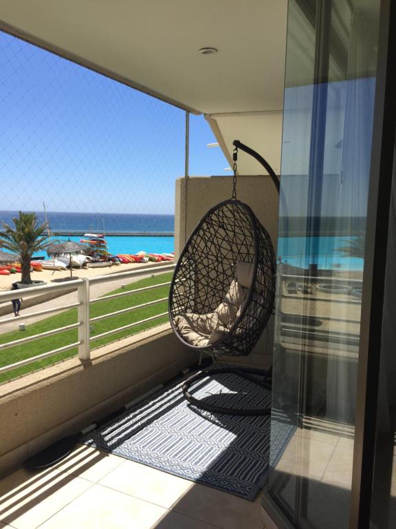 a hammock on a balcony with a view of the ocean at Departamento San Alfonso in Algarrobo
