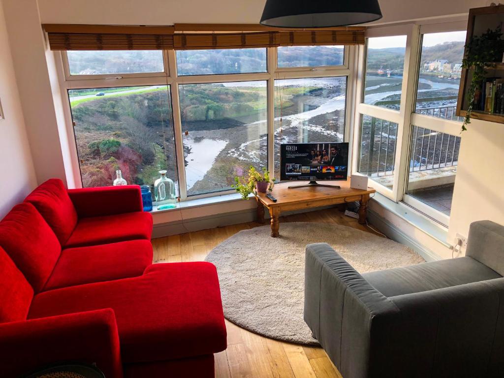 a living room with a red couch and a table and a large window at Clifden Bay Apartment in Clifden