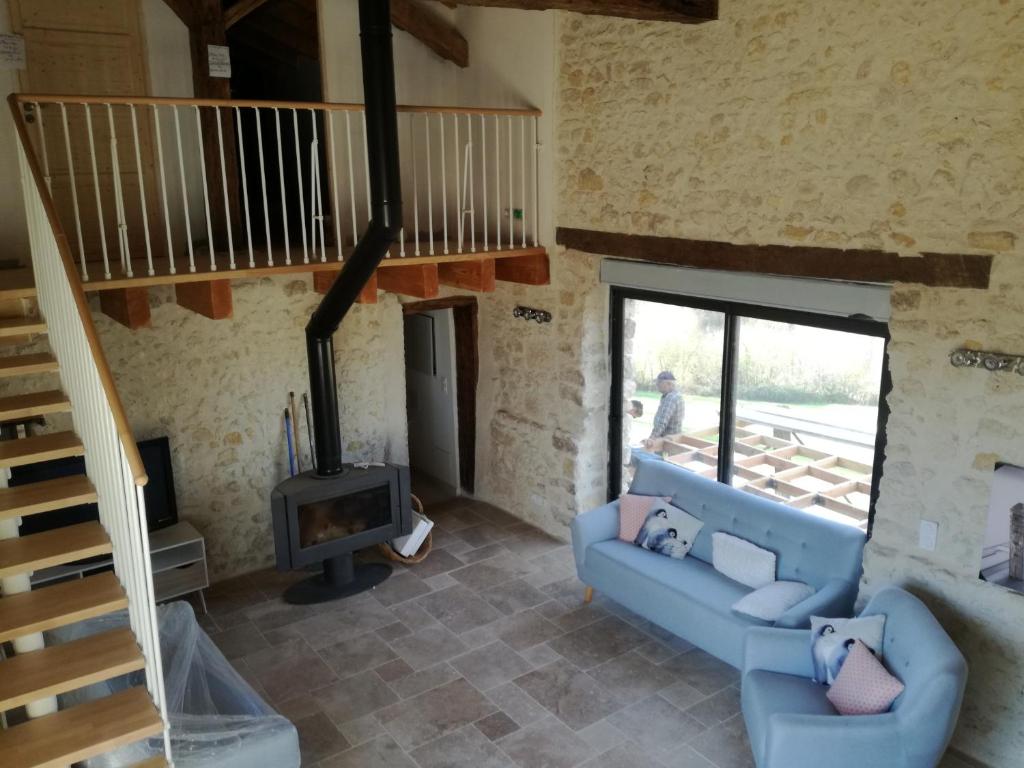 a living room with a blue couch and a wood stove at Gîte de caractère en pleine nature in Bourg-de-Visa