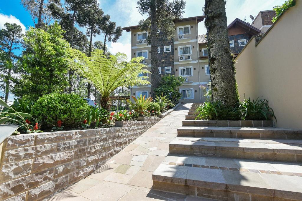 een loopbrug voor een gebouw met bomen en planten bij Apartamento Foss in Gramado