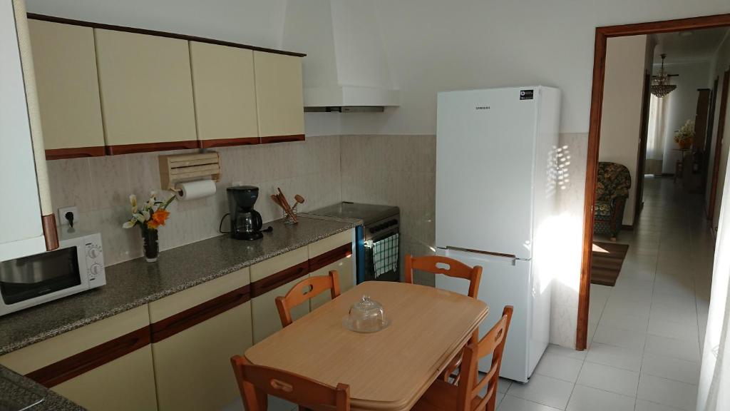 uma cozinha com uma mesa e um frigorífico branco em AL Visconde em Ponta Delgada