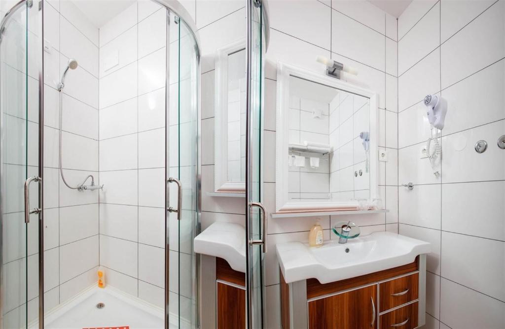 a bathroom with a shower and a sink and a mirror at Ark Beach Apartments in Split