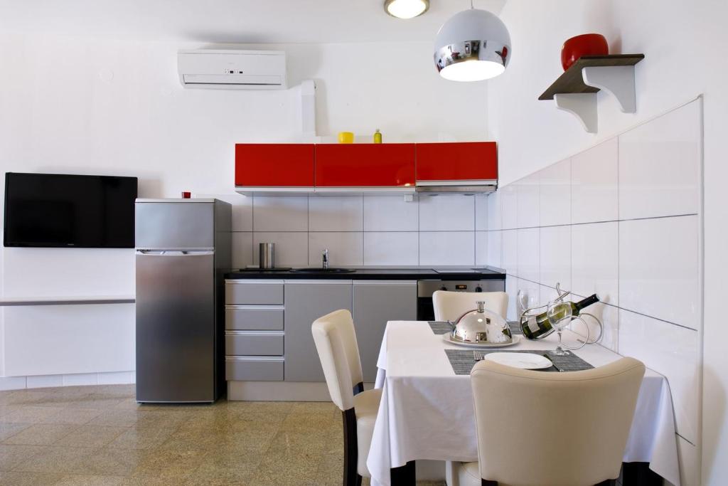 a kitchen with a table with chairs and a refrigerator at Ark Beach Apartments in Split