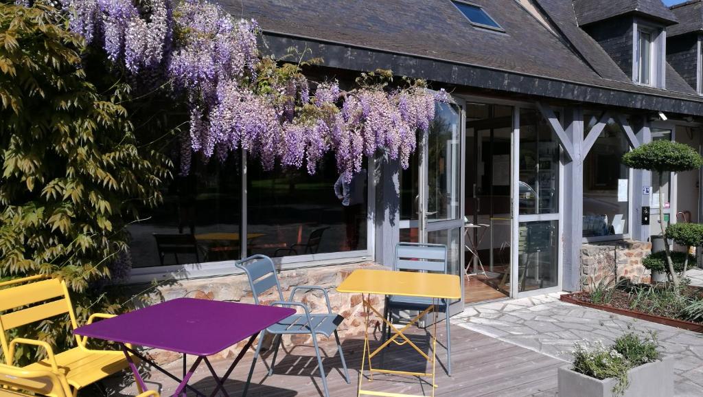 - une table de pique-nique et des chaises sur une terrasse avec des glycines pourpres dans l'établissement Logis Hôtel Lodge La Valette, à Cesson-Sévigné