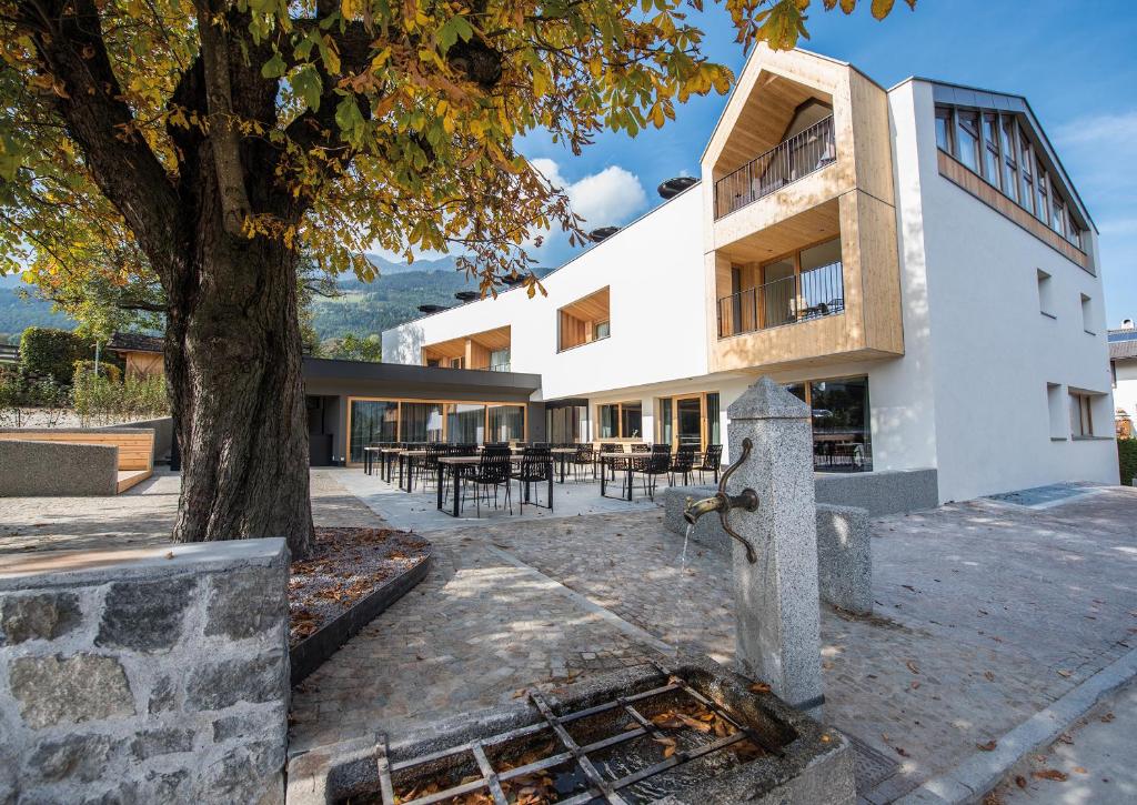 un edificio con un árbol delante de él en Dining & Living Alpenrose, en Bresanona