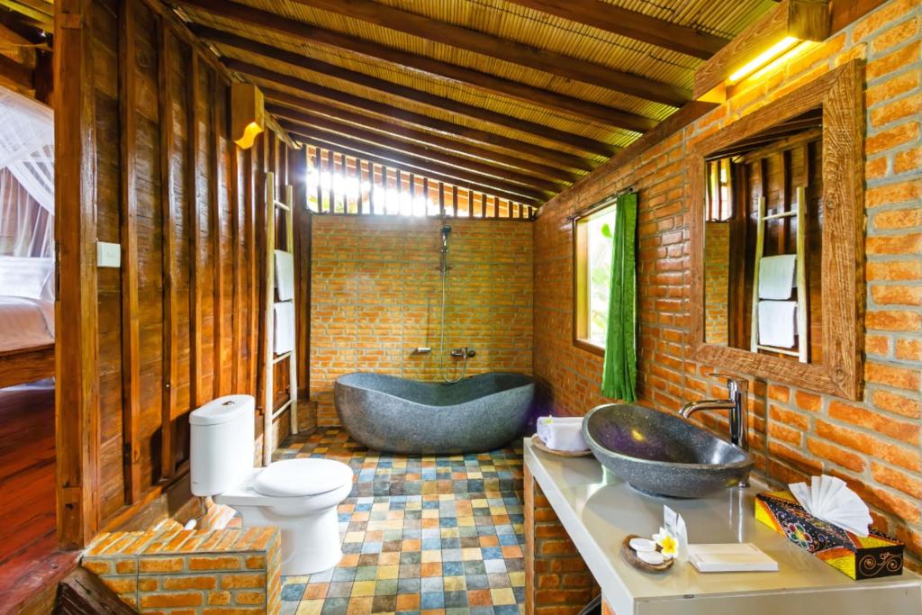 a bathroom with a tub and a sink and a toilet at Bali Natha Beach Front in Canggu