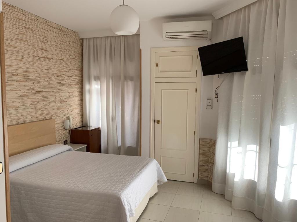 um quarto com uma cama e uma televisão de ecrã plano em Hostal Cervantes em Valdemoro