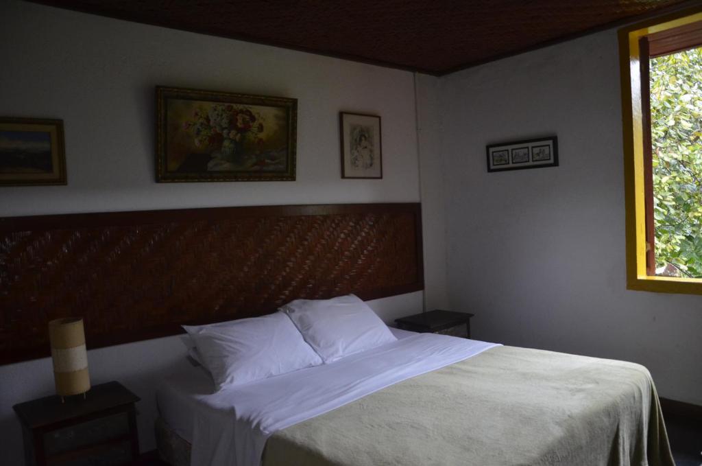 1 dormitorio con 1 cama con sábanas blancas y ventana en Pouso da Passagem B&B en Mariana
