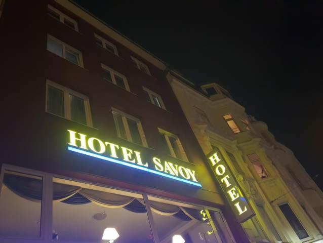 una señal de hotel en el lateral de un edificio por la noche en Hotel Savoy Bonn en Bonn