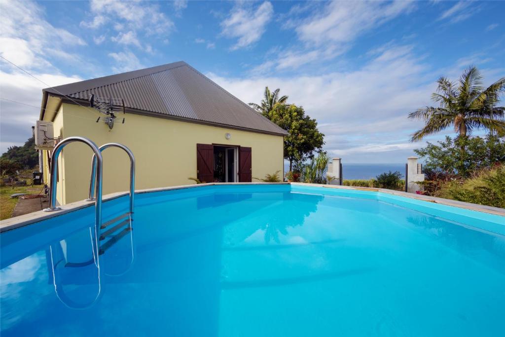 a swimming pool in front of a house at Gîte "Bassin Julien" in Saint-Joseph