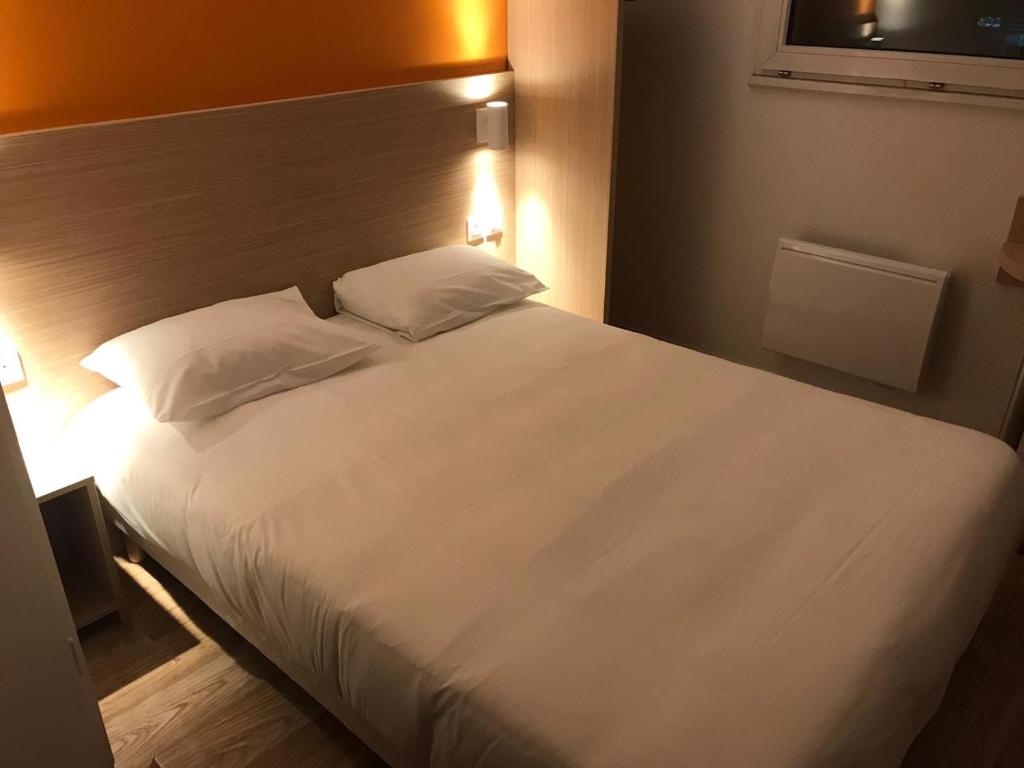 a bedroom with a large bed with white sheets and pillows at Première Classe Reims Ouest - Tinqueux in Reims