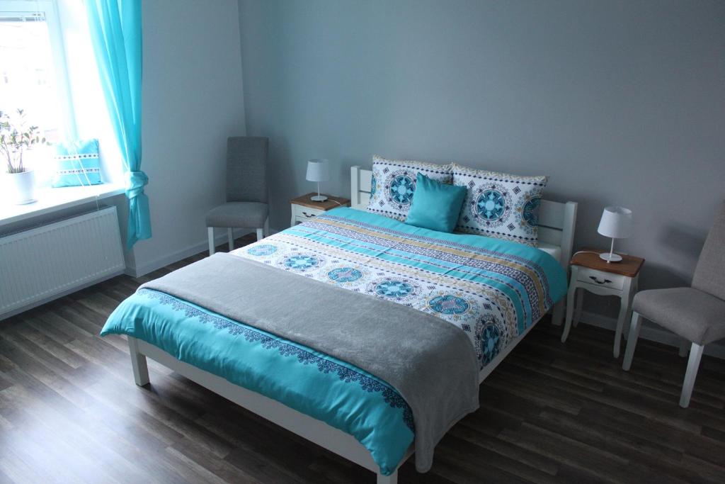 a bedroom with a bed and two chairs and a window at Apartament Poniatowskiego in Radom