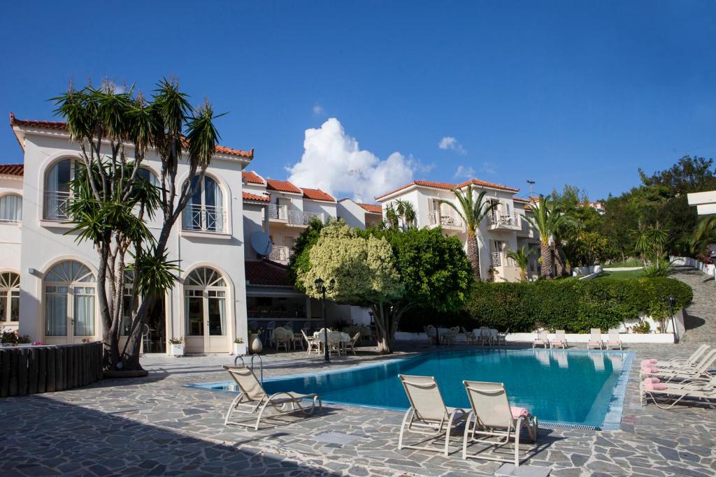 een huis met een zwembad met stoelen en bomen bij Princess Hotel in Lassi