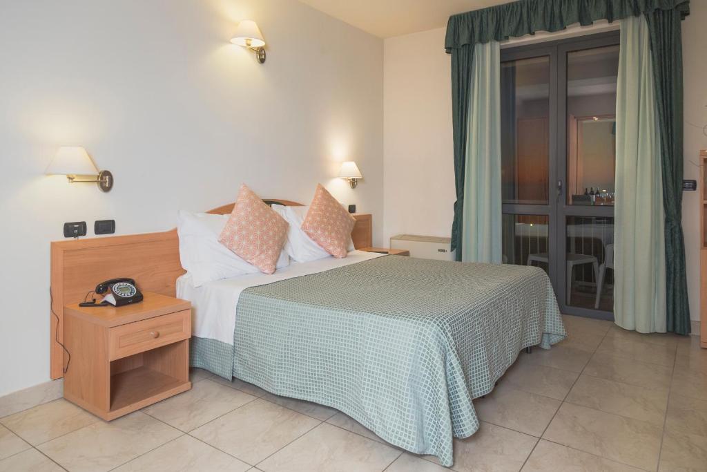 una camera da letto con un letto e un tavolo con un orologio sopra di Hotel Bixio a Lido di Camaiore