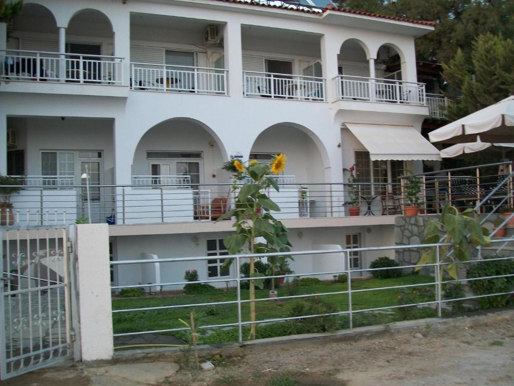 Un grand bâtiment blanc avec un balcon et une plante dans l'établissement Paschalia sea view studios, à Psakoudia