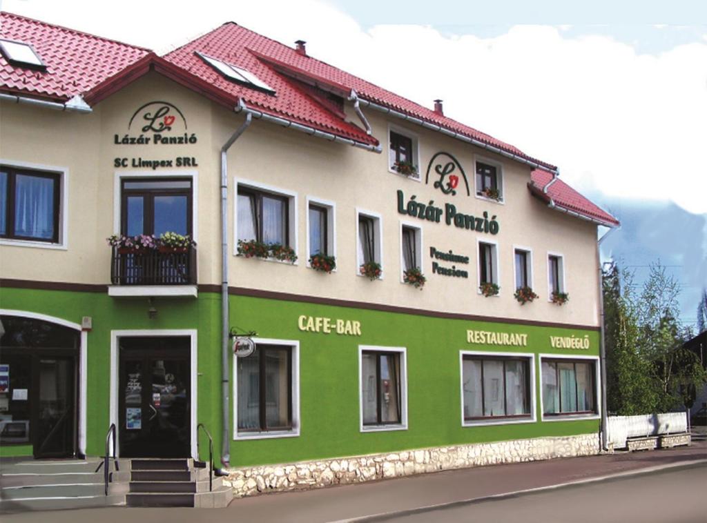 un bâtiment vert et blanc avec un café-bar dans l'établissement Lázár Pension & Restaurant, à Gheorgheni