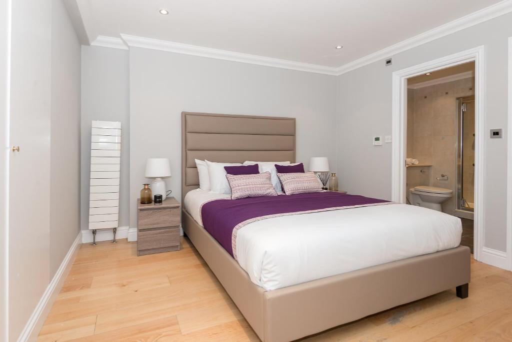 ロンドンにあるOne bedroom Hyde Park Apartmentの白いベッドルーム(紫色の枕を使用した大型ベッド1台付)