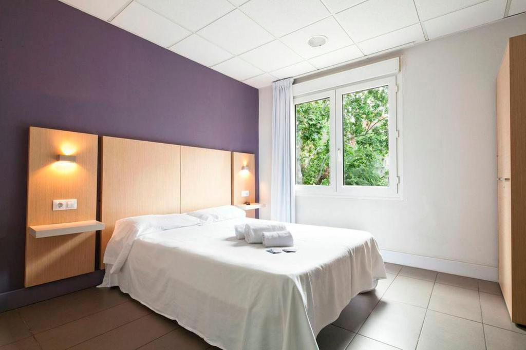 a bedroom with a white bed and a window at Putxet by gaiarooms in Barcelona