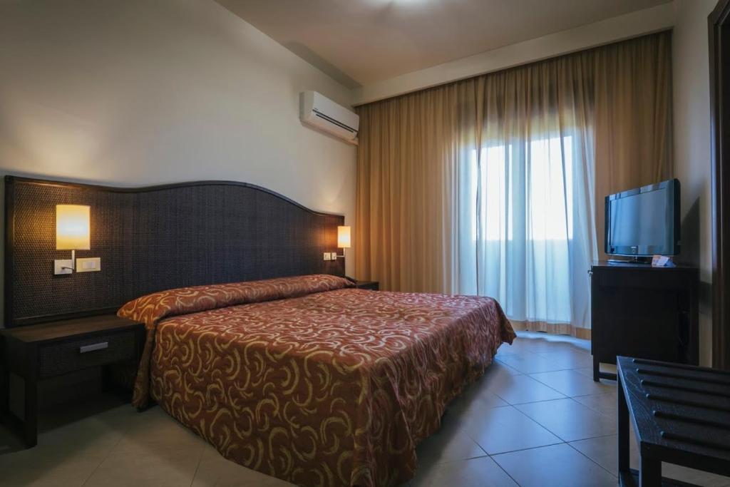 a hotel room with a bed and a television at Hotel Costa Azul in Balestrate
