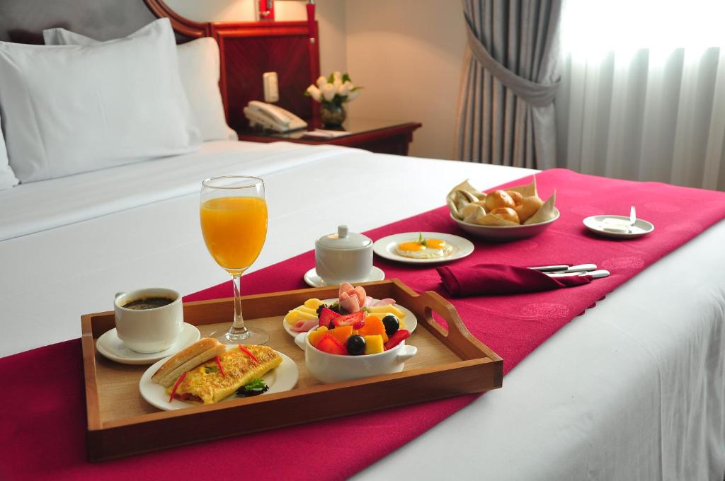 ein Tablett mit Essen und einem Getränk auf dem Bett in der Unterkunft Kingdom Hotel in Lima